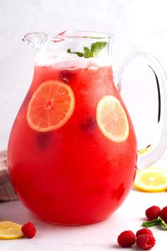 a pitcher filled with red liquid and sliced lemons