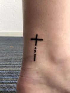 a small cross tattoo on the ankle that reads, i love you in black ink