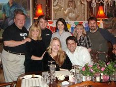 a group of people posing for a photo in front of a table with food and drinks