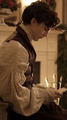 a woman sitting on a chair in front of a fire place holding a remote control