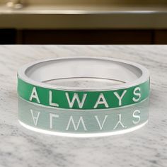 a green and white wristband with the words always on it sitting on a marble surface