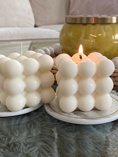 two white candles sitting on top of a glass table