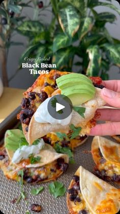 a person is grabbing an avocado from a black bean tacos