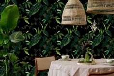 a table with two vases and plates on it in front of a green wallpaper