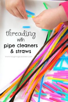 a child playing with pipe cleaners and straws on a white tray filled with colored sticks