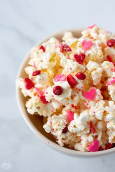 a bowl filled with white and red candy caned popcorn on top of a table