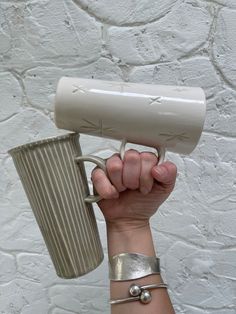 a person holding a hair dryer in their hand with a cup next to it