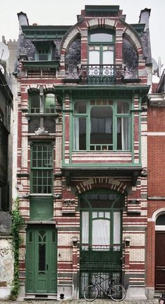 an old brick building with green shutters and bicycles parked in front of the windows