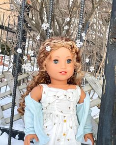 a doll standing next to a fence in the snow