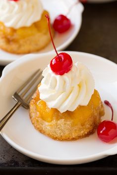 three small desserts with whipped cream and cherries on them are sitting on white plates