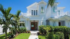 a large white house with palm trees in the front yard and walkway leading up to it