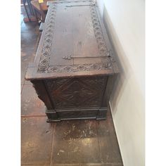 an old wooden table with carvings on the top and bottom, sitting against a wall