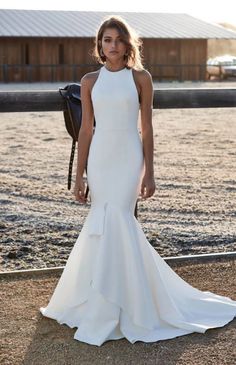 a woman in a white wedding dress posing for the camera with her hand on her hip