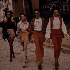 three women are walking down the street with one woman wearing an orange skirt and white shirt