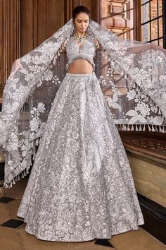 Silver attached cancan lehenga with metallic thread, sequin embroidery in flower pattern. Paired with plunge V neck embroidered padded blouse and tassel border embroidered dupatta. - Aza Fashions Silver Lehenga, Wedding Lenghas, Seema Gujral, Mehendi Outfit, A Royal Affair, Sangeet Outfit, Net Embroidery, Punjabi Bride, Silver Embroidery