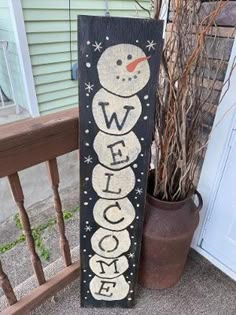 a welcome snowman sign sitting next to a potted plant in front of a house