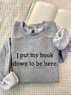 Show off this bookish style with our custom embroidered  I Put My Book Down To Be Here sweatshirts. Expressing your love for literature with our funny and uniquely designed bookish sweatshirts, perfect for Book Lovers and avid readers alike. Browse our collection of, custom embroidered sweatshirts and discover the perfect Book merch to express your passion for reading! :) FREE SHIPPING Please allow up to 1-3 business days for the product to be made. * 50% cotton, 50% polyester * Pre-shrunk * Classic fit * 1x1 athletic rib knit collar with spandex * Air-jet spun yarn with a soft feel and reduced pilling * Double-needle stitched collar, shoulders, armholes, cuffs, and hem 10% of profits are donated to nonprofit organization. CARE instructions: Machine wash warm, inside out (to protect the em Mode Old School, Gifts For Book Lovers, Lover Sweatshirt, Book Clothes, Embroidered Gifts, Embroidered Crewneck, Embroidered Clothes, Funny Sweatshirts, Embroidered Sweatshirts