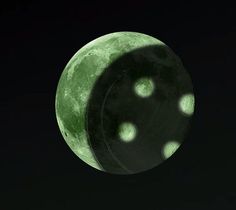 the moon is lit up in the dark sky with green lights on it's side