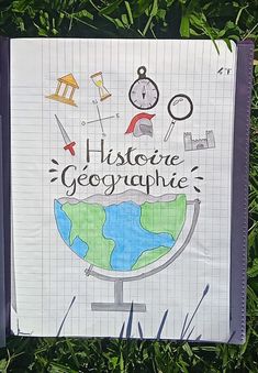 a notebook with the words historie geographie written on it in front of green grass