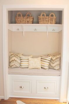 a white bench with pillows and baskets on it