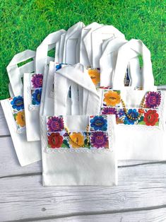 six white bags with colorful flowers on them are sitting on the ground in front of some green grass