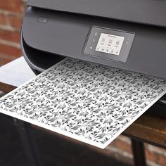 a close up of a printer on a table with paper in front of the printer