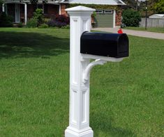 a white mailbox in the grass near a house