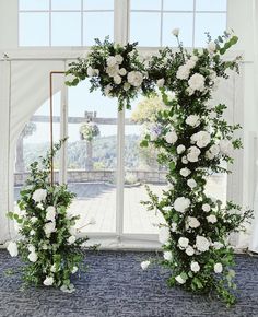 two white roses and greenery are arranged in front of an open window at the end of a ceremony