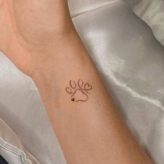 a woman's arm with a dog paw tattoo on the left side of her wrist