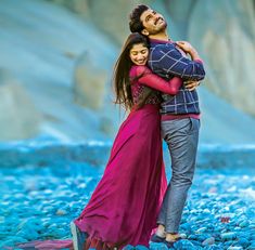 a man and woman embracing each other in front of blue rocks