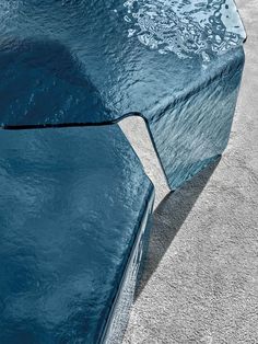 an artistic table made out of blue glass with water flowing over the top and below it