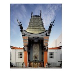 the entrance to an orange and white building with sculptures on it's sides, in front of a blue sky