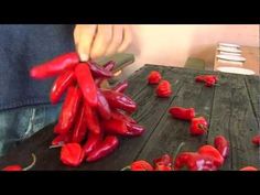 someone is cutting up red peppers on a wooden table