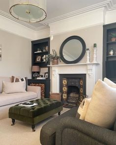 a living room filled with furniture and a fire place in front of a mirror on the wall