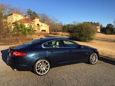 a blue car is parked on the side of the road in front of a house