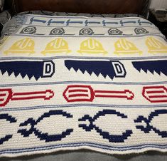 a crocheted blanket with construction hats and chains on it, sitting on top of a bed