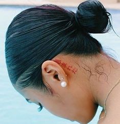 a woman with a tattoo on her ear next to a swimming pool