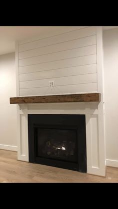 an empty room with a fireplace and white walls