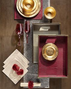 the table is set with red and gold plates, napkins, and wine glasses