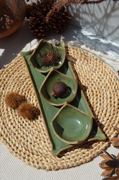 two bowls are sitting on top of a wicker place mat with pine cones in the background