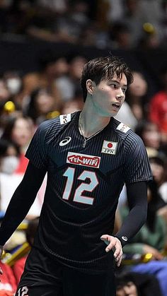 a male volleyball player in action on the court with fans watching from the sidelines