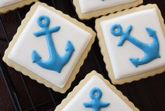 four decorated cookies with blue and white icing on a cooling rack next to each other