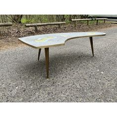 a table that is sitting in the middle of some gravel and wood benches behind it