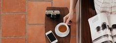 a person sitting at a table with a cup of coffee and cell phone on it