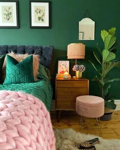 a bedroom with green walls and a bed covered in blue velvets, pillows and blankets