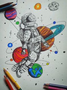 a drawing of an astronaut floating in space surrounded by planets and other objects, with colored pencils on the table