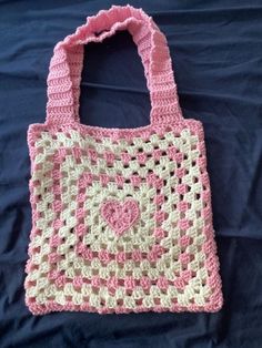 a pink and white crocheted bag laying on top of a blue sheet,