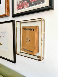 three framed photographs hang on the wall above a couch with a book in it's glass case