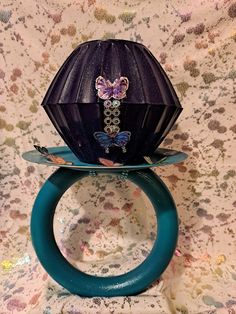 a purple vase sitting on top of a blue plate with a butterfly decoration on it