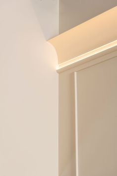 the light is on above the door in the room that has white walls and trim